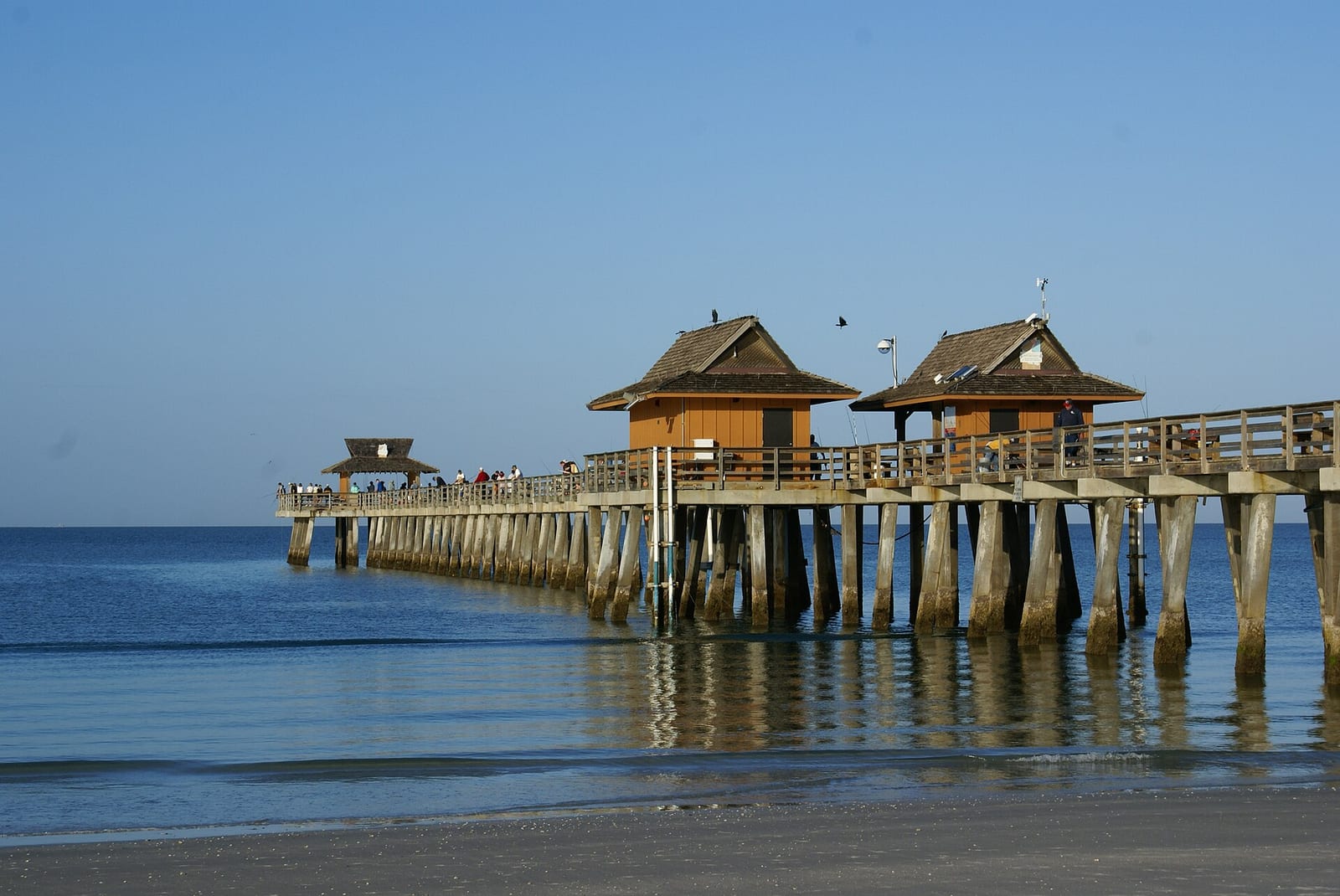 3rd Avenue North Beach: wooden pier with pavilion structures extending into calm ocean water