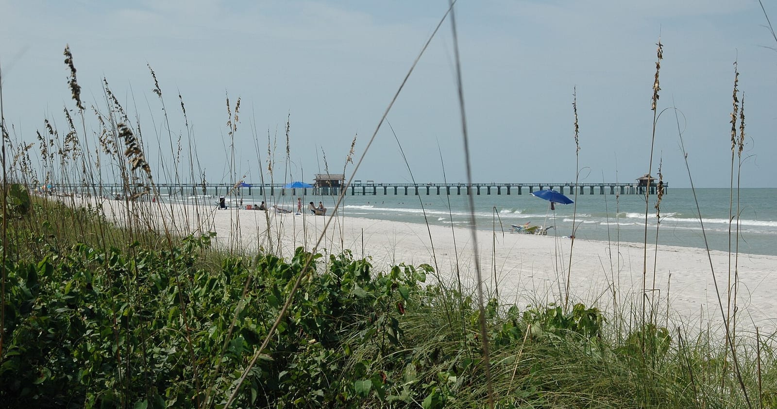 3rd Avenue North Beach: beach with dune vegetation, pier, sailboat, and calm ocean water