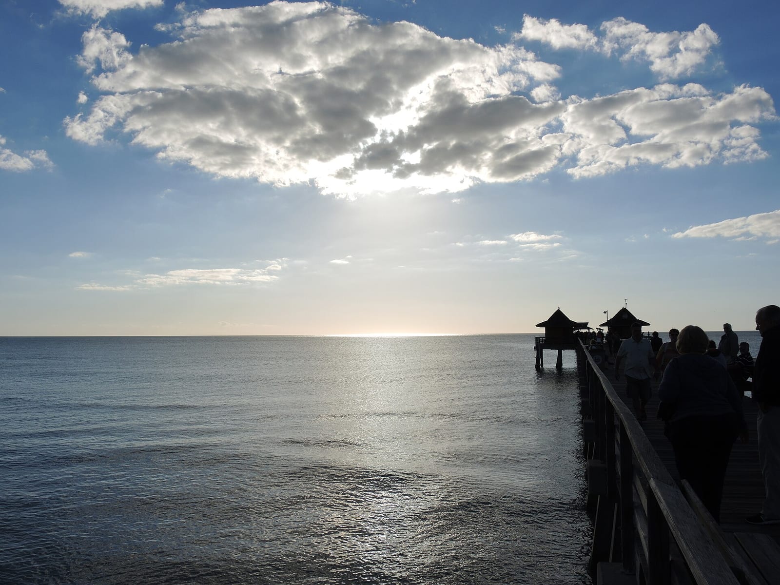 9th Avenue South Beach: pier extending into ocean with silhouetted visitors, cloudy sky