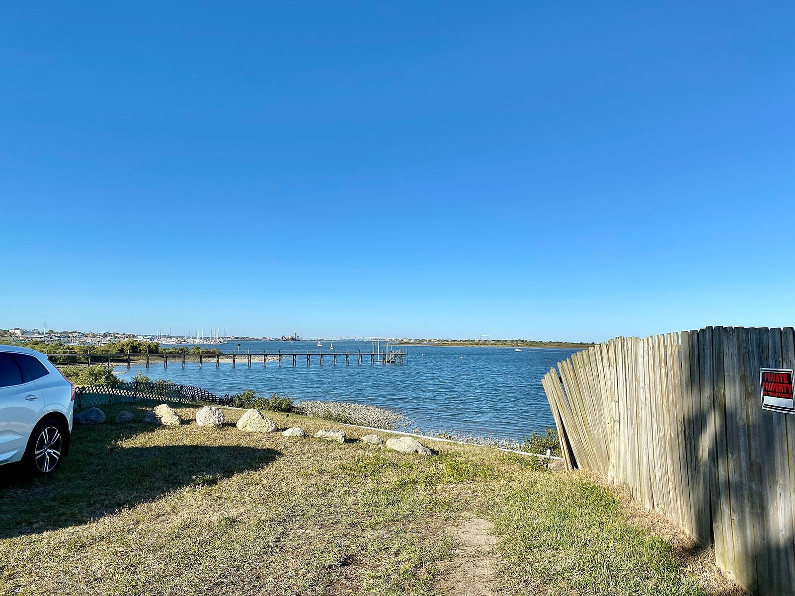 Anastasia State Park: coastal waterway with pier, parked car, grassy shore, wooden fence
