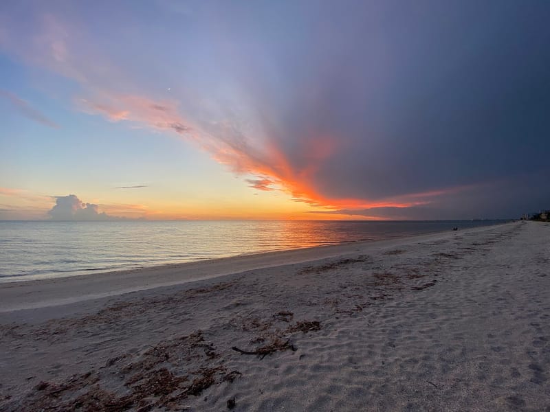 Bonita Beach: sandy beach at sunset with calm ocean and colorful sky