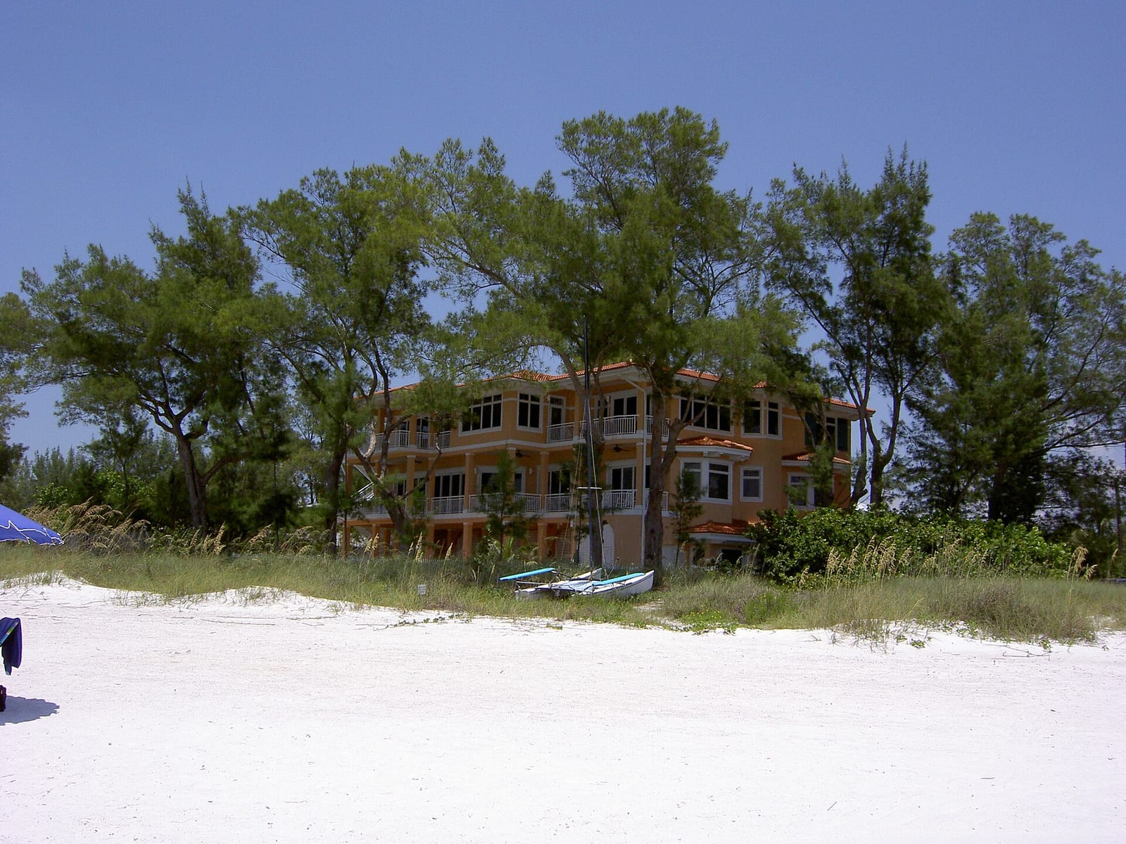 Bradenton Beach: abandoned orange building on beach with sand dunes and trees