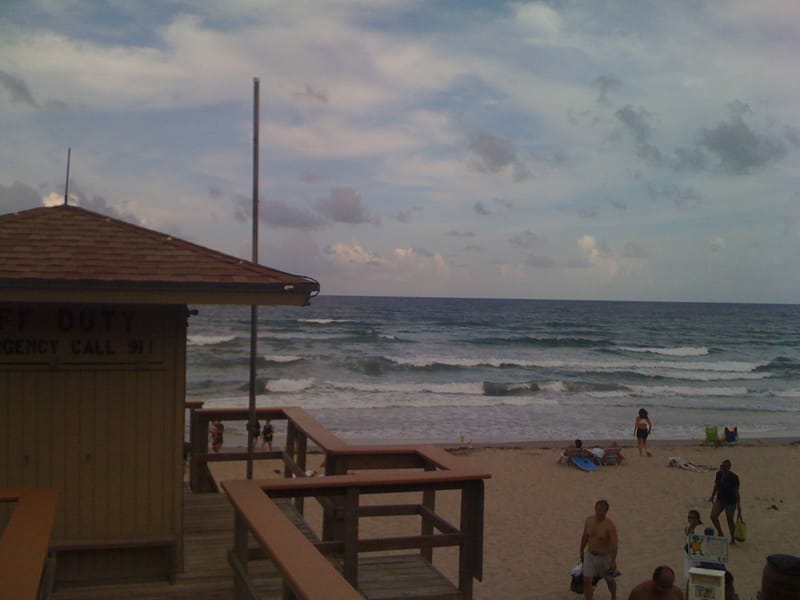 Delray Public Beach: beach with lifeguard station, visitors in water and sand, cloudy sky