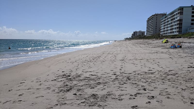 Juno Beach: sandy beach with ocean, waves, beachgoers, and coastal high-rise buildings