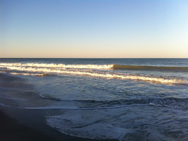 Patrick AFB Beach: ocean waves breaking on sandy beach at sunrise or sunset