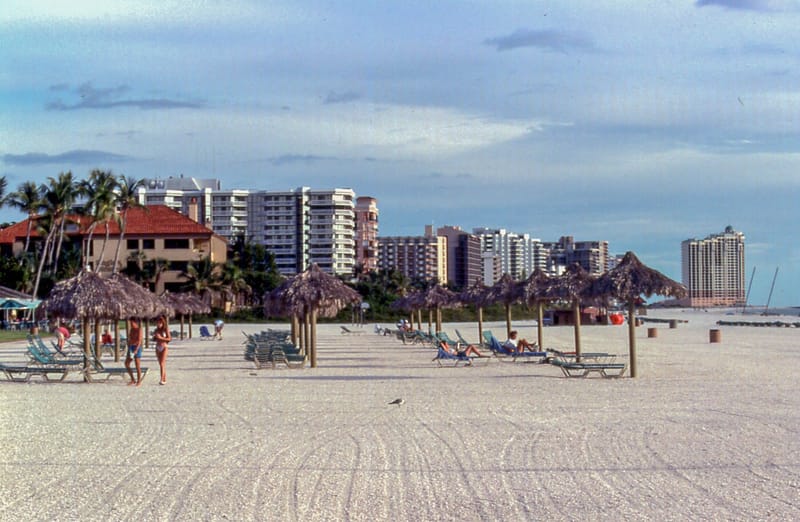 South Marco Beach: sandy beach with lounge chairs, umbrellas, and high-rise buildings behind