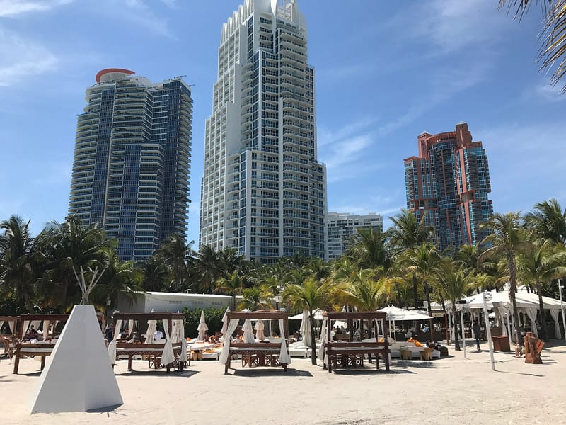 South Pointe Beach: beach with cabanas, palm trees, high-rise buildings in background
