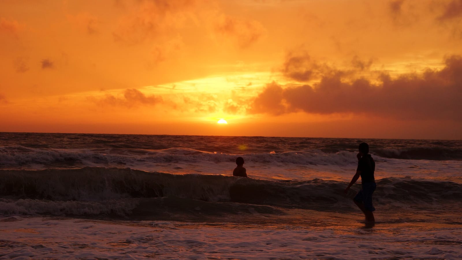 Vanderbilt Beach: sunset over ocean with silhouetted surfers in water