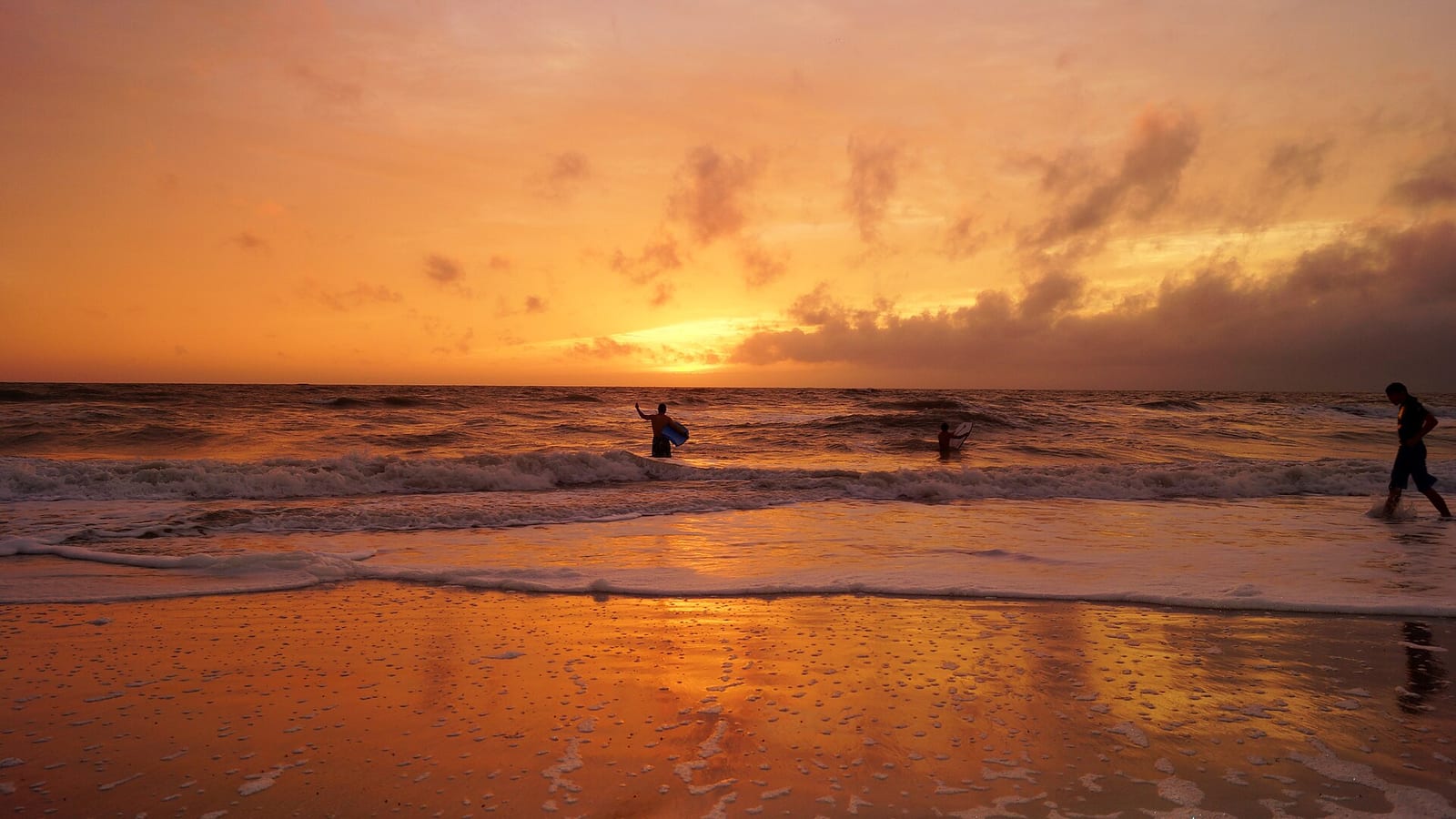 Vanderbilt Beach: sunset over ocean with silhouetted surfers in water and on beach